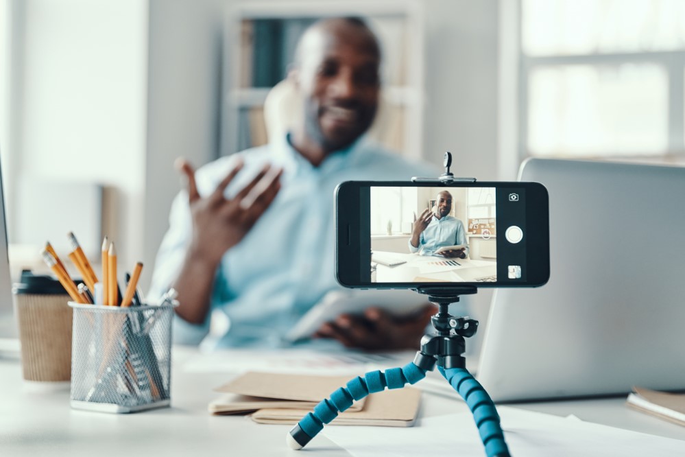 Photo of man filming a video on his smartphone