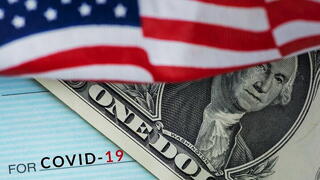 Image of American flag, US one dollar bill, check made out to COVID-19