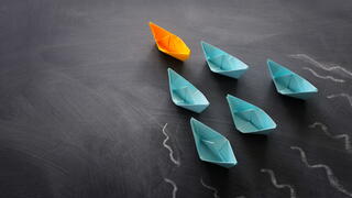 Image of paper boats with one leading 