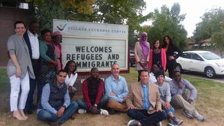 People standing around sign that reads immigrants welcome